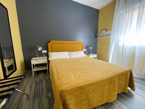 Chambre double moderne à la Pensión Alicante San Nicolás avec tête de lit moutarde, mur d'accent gris et accents jaunes