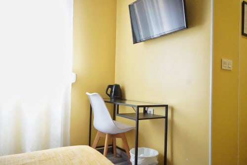 Chambre moderne à la Pensión Alicante San Nicolás aux murs jaunes, chaise blanche, bureau avec TV et espace de travail
