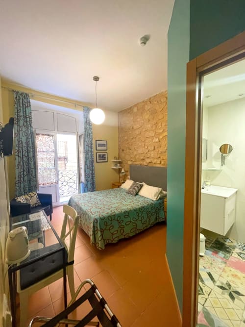 Camera da letto luminosa presso Pensión Alicante San Nicolás con letto matrimoniale, accesso al balcone, pareti gialle, parete in sughero e bagno en-suite