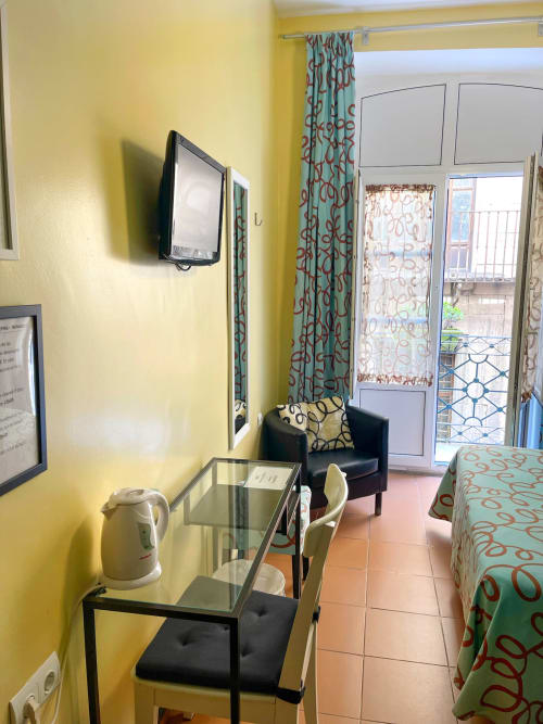Camera d'hotel giallo brillante presso Pensión Alicante San Nicolás con accesso al balcone, TV, scrivania di lavoro e arredi con motivi decorativi