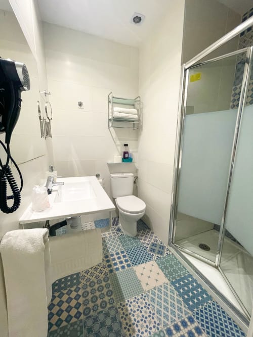 Bagno moderno presso la Pensión Alicante San Nicolás con doccia, WC, lavandino, piastrelle decorate e pareti in piastrelle bianche stile subway