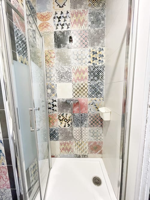 Cabina doccia moderna con piastrelle decorative a motivi nel bagno dell'hotel Pensión Alicante San Nicolás