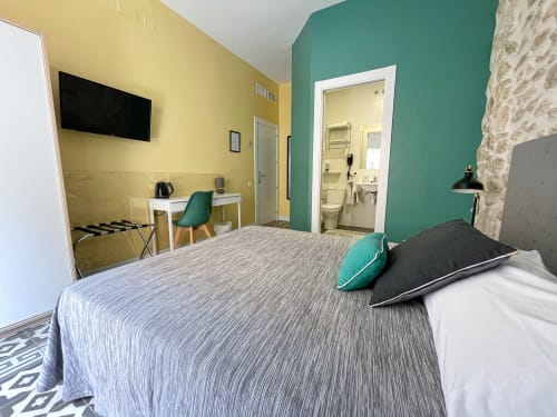 Camera moderna presso la Pensión Alicante San Nicolás con pareti gialle e blu teal, letto queen, scrivania di lavoro e bagno privato