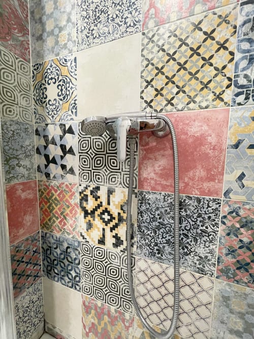 Parete doccia con piastrelle patchwork colorate e motivi geometrici nel bagno dell'hotel Pensión Alicante San Nicolás