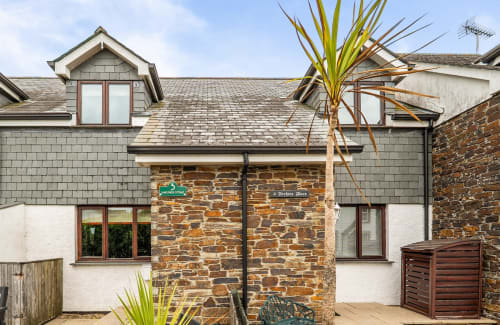 Stone cottage exterior at 2 Doves Holiday Property in Exeter with white walls, slate roof, and garden entrance