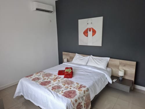 Modern bedroom at Gerards & Angel, Flic en Flac with wooden bed frame, white linens, dark accent wall, red lip artwork, and
