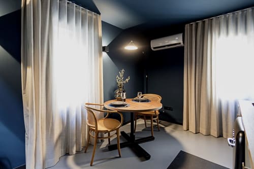 Modern dining area in Porto hotel duplex with wooden table, rattan chairs, dark walls, and sheer curtains