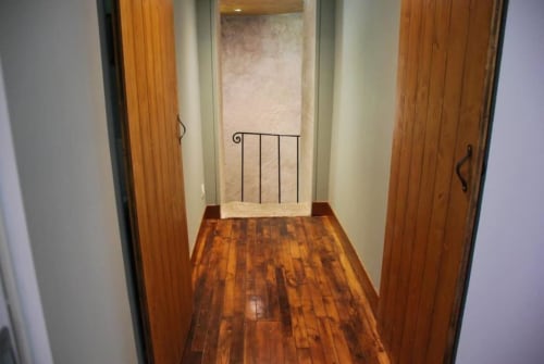 Couloir en bois du Château de Vaux Morvan avec portes donnant sur une terrasse surplombant le jardin, ornée d'une rampe en fer