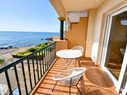 Sea view balcony at Apartamentos El Calón Playa with dining table, chairs, and Mediterranean coastline in Cuevas del