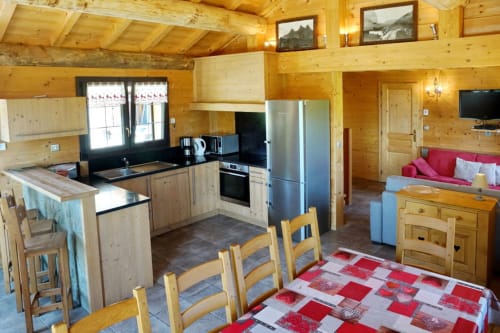 Grand Loup room at Chalet La Louvière with wooden interior, modern kitchen, dining area, and red sitting area with mountain