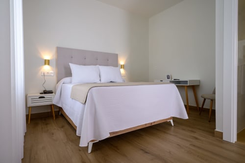 Dormitorio moderno en Suite Superior del Hotel Alcazaba Salobreña con cama, mesitas de noche y escritorio de madera