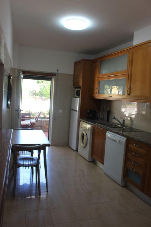 Modern kitchen with wooden cabinets, stainless steel appliances, dining area and terrace access at Seahorse House, Tavira
