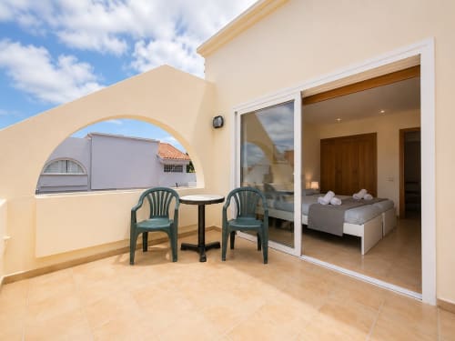Terraza con zona de estar en Villa Paloma, hotel Corralejo, con vistas al dormitorio con ventana arqueada