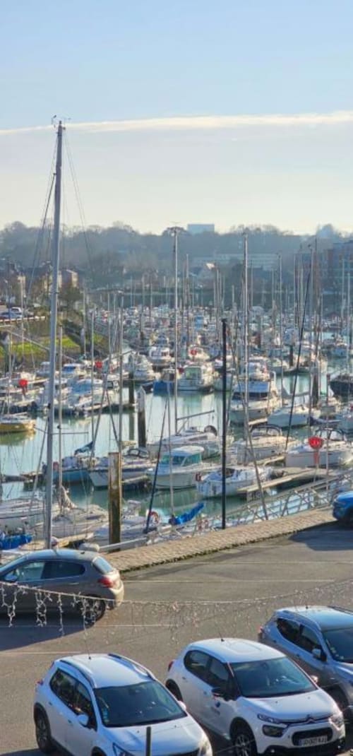 Voiliers amarrés au port de Saint-Valéry-en-Caux avec paysage urbain et voitures garées