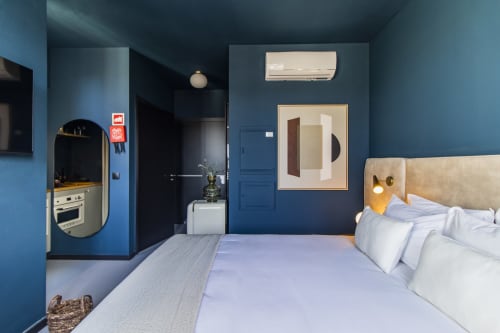 Estúdio compacto em hotel no Porto com paredes azuis, cabeceira bege, kitchenette e comodidades modernas