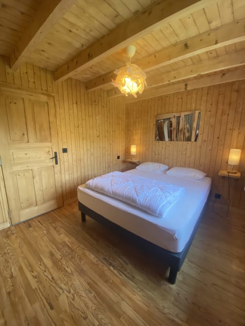 Cozy wooden bedroom in Chalet Les Georgières, Notre-Dame-de-Bellecombe, featuring a queen bed with white linens and warm