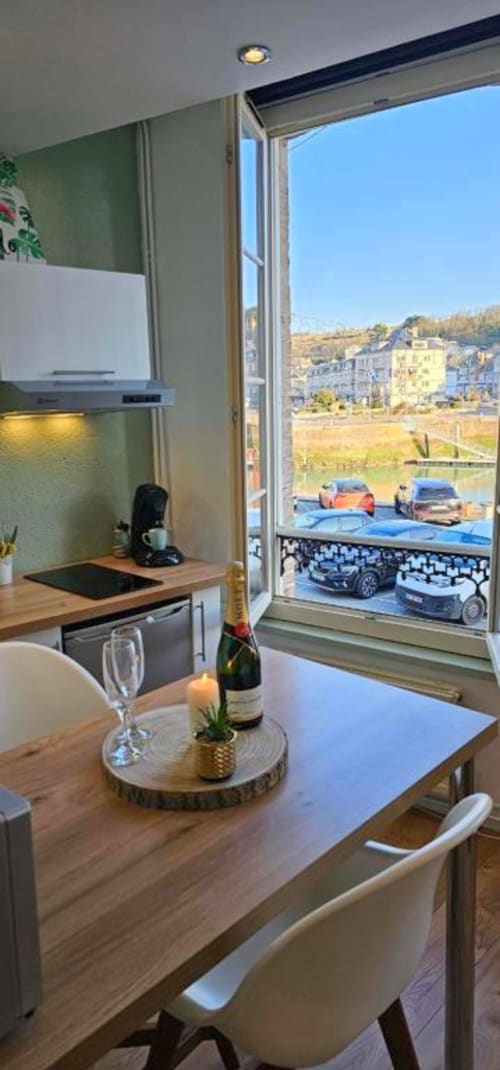 Cuisine moderne avec table à manger, bouteille de champagne et vue mer sur le port de Saint-Valery-en-Caux et voitures garées