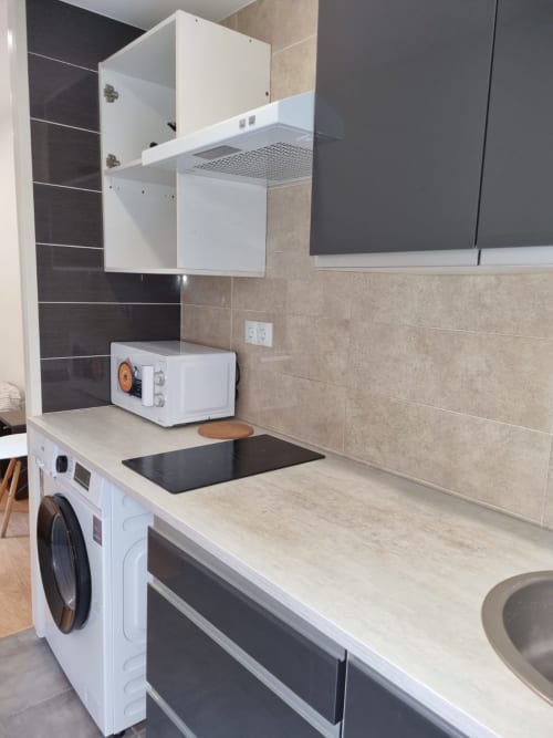 Compact kitchen with washer, microwave, and sink in Hostal Porto Mar private room, Salou