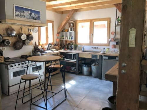 Modern kitchen with wooden beams, dining table, and cooking equipment in Les Chalets de l'Eau Rousse cottage, Celliers,