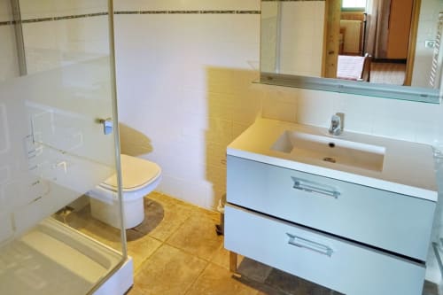 Modern bathroom in Petit Loup room at Chalet La Louvière with white vanity, toilet, shower, and yellow tile flooring
