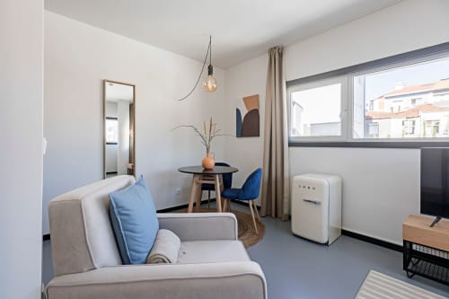 Apartamento estúdio moderno no Porto com sala de estar confortável, área de refeições, kitchenette e vista para o jardim através de grandes janelas