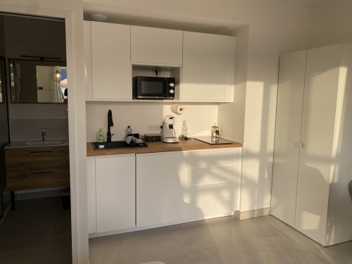Kitchenette moderne blanche avec plan de travail en bois, micro-ondes, cafetière et appareils électroménagers dans le Studio 5 de La Maison Blanche