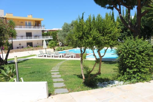 Seahorse House pool view with manicured garden, lounge chairs, and yellow-topped villa in Tavira, Portugal