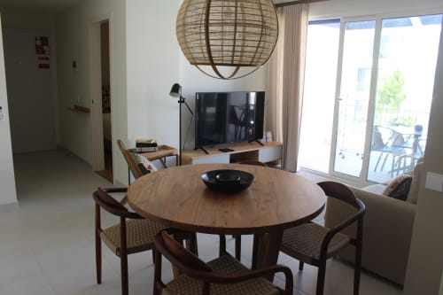 Modern apartment dining area at Break Lovers, Tavira with round wood table, woven pendant lamp, and sliding glass doors