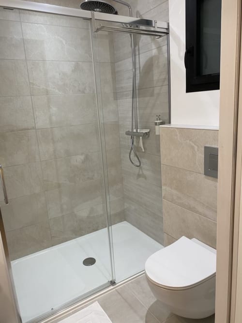 Modern bathroom with walk-in shower, toilet, and beige tile at La Maison Blanche, Bouguenais, FR