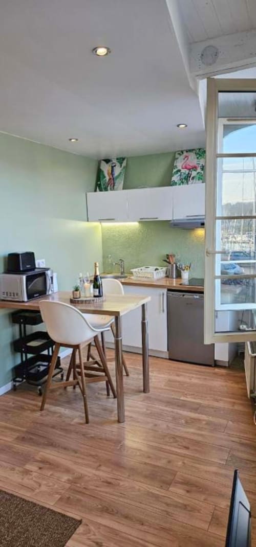 Kitchenette moderne aux placards blancs, coin repas et vue sur mer à l'appartement La Jungle à Saint-Valery-en-Caux