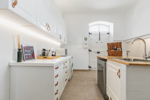 Cozinha moderna branca com bancadas em madeira e puxadores em cobre na Villa Casa Rural CSA em Camarnal, Portugal
