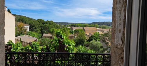 Vue du balcon sur le village de Plaissan en Provence : toits en terre cuite, collines verdoyantes et paysage bucolique de Chez Laure