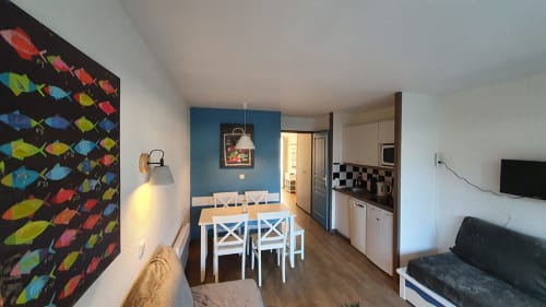 Modern apartment kitchen and dining area with sea view in La Fôret-Fouesnant, featuring white table, blue accent wall