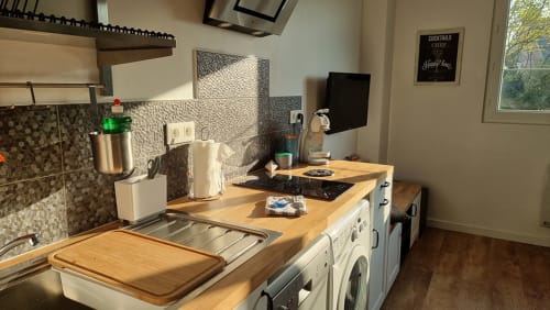 Modern kitchen in Ô LOCH apartment at Location Vacances Finistère Sud with wooden counters, white appliances, and patterned
