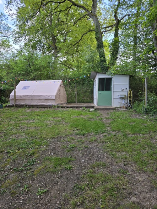 Tente de glamping et cabane utilitaire nichées sous de grands arbres au Domaine Trianon, Villandry