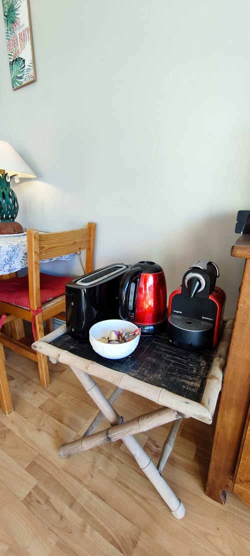 Appareils de cuisine et articles de petit-déjeuner sur table dans appartement à La Trinité sur Mer avec chaises en bois et vue sur mer