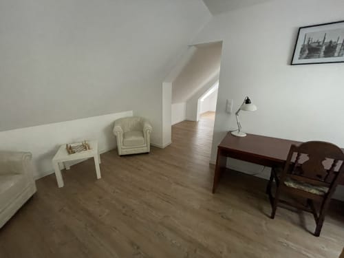 Spacious cottage living room at Les Gites De Flaubert with cream armchair, desk, and wooden furnishings