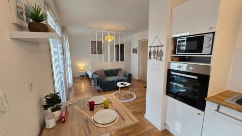 Modern apartment kitchen and living area at Ô Kastel in La Fôret-Fouesnant with dining table, sofa, and equipped kitchenette