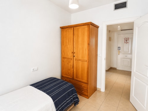 Dormitorio con armario de madera y cama individual en Apartamentos El Calón Playa, Cuevas del Almanzora