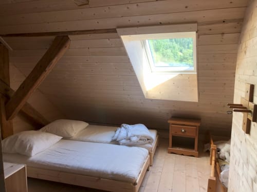 Bright attic bedroom at Les Chalets de l'Eau Rousse with skylights, wooden beams, mountain views, and wooden furnishings