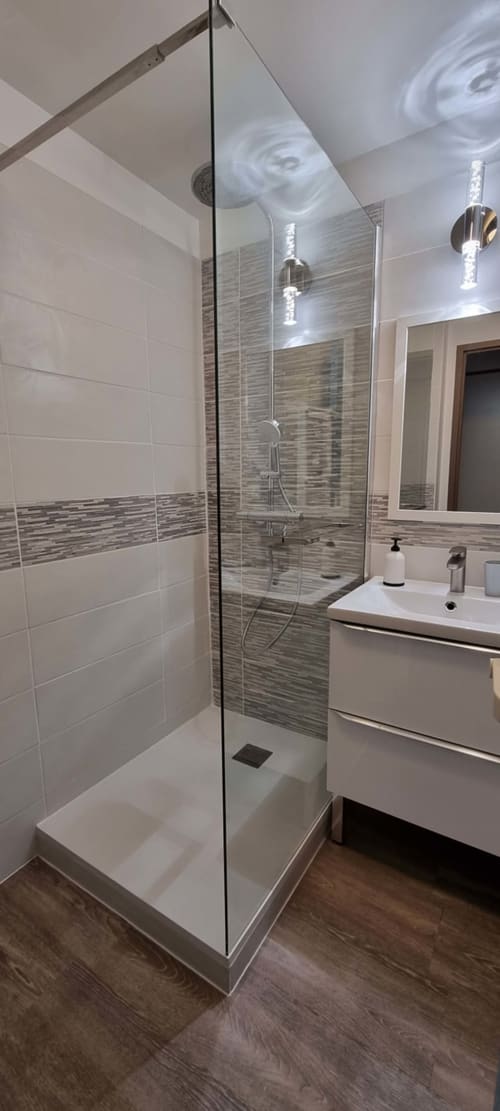 Modern bathroom with walk-in shower, white vanity, and grey tile accent at Ô CAP COZ apartment, La Fôret-Fouesnant