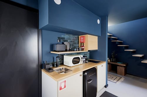 Modern kitchenette in Porto hotel duplex with white cabinetry, wooden countertop, microwave, and blue accent walls