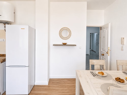 Modern kitchen in Apartamentos El Calón Playa with white refrigerator, dining table, and coastal apartment décor