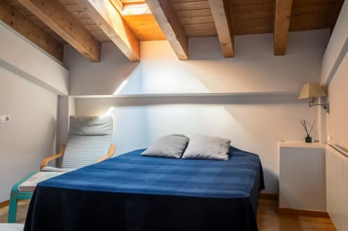 Acogedor dormitorio en apartamento de montaña en Front Beach Villas, Montgat, con cama azul, vigas de madera y tragaluz natural