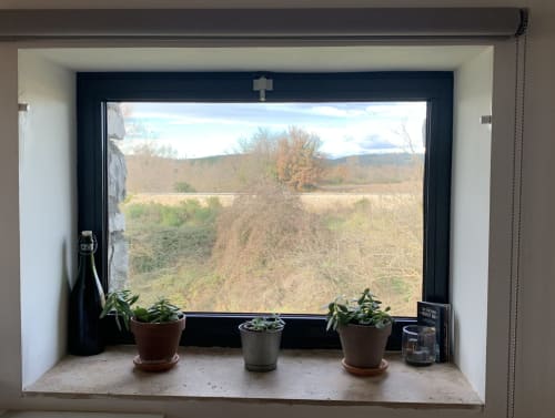 Vue de la campagne par la fenêtre de la Magnanerie de Sainte Croix avec plantes en pots sur le rebord