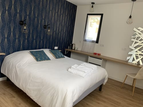 Modern double bedroom at La Maison Blanche B&B in Bouguenais with blue patterned accent wall, white bed, and desk.