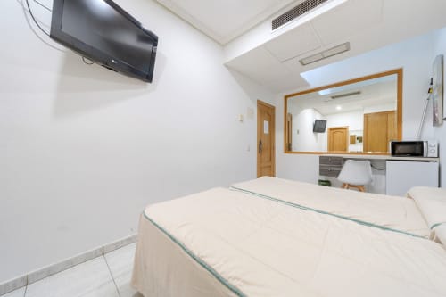 Habitación doble con camas gemelas en Hostal El Molino, Collado Villalba. Incluye escritorio, espejo, TV y comodidades modernas
