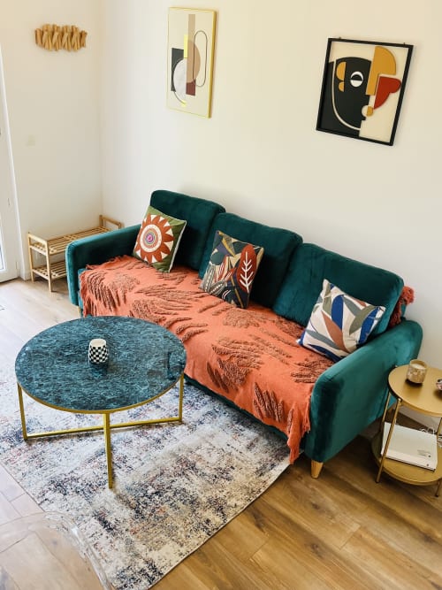 Salon cosy de chaumière moderne avec canapé bleu canard, plaid orange, coussins à motifs et art abstrait à Étretat