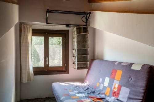 Dormitorio acogedor en apartamento de Montgat con ropa de cama colorida, puertas de madera y vistas a la montaña desde la ventana