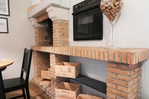 Kitchenette en briques avec four intégré et présentoir de cartons de vin aux Gîtes Saint Valery En Caux